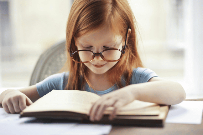 Rothaariges Mädchen mit Brille liest ein Buch